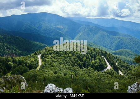 Luftaufnahme über Berge mit Wald bedeckt und eine kurvenreiche Straße Stockfoto