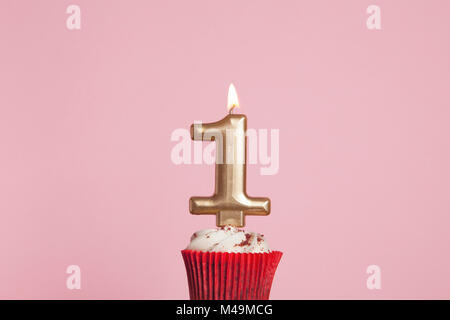 Nummer 1 goldene Kerze in eine Cupcake gegen ein Pastell rosa Hintergrund Stockfoto