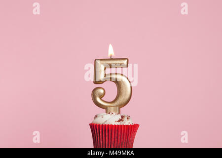 Nummer 5 Gold Kerze in eine Cupcake gegen ein Pastell rosa Hintergrund Stockfoto