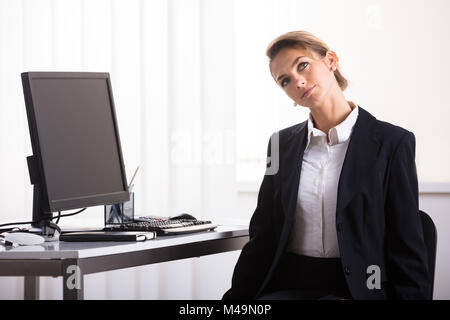 Junge Geschäftsfrau Sitzen auf Stuhl Ausübung ihren Hals im Büro Stockfoto