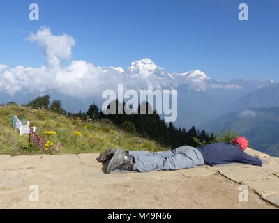 Wanderer entspannen auf Poon Hill, Dhaulagiri Bereich auf dem Hintergrund - einer der am meisten besuchten Himalayan Aussichtspunkte in Nepal, Blick auf die schneebedeckten Himalaya Stockfoto