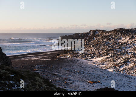 Atlantik Wellen gegen die verschneite schwarzen Sand-/Kiesel Djúpalónssandur Strand auf der Halbinsel Snaefellsnes im Westen von Island im Winter Stockfoto