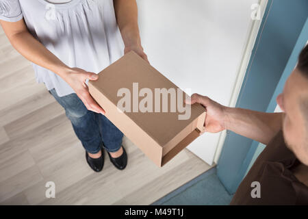 Nahaufnahme der Frau unter Karton ab Lieferung Mann Stockfoto