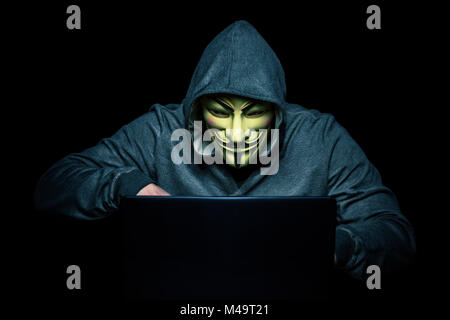 Mailand, Italien, Februar 2018: Hacker Verschleiß anonymus Maske mit Notebook im Dunkeln. Editorial Foto. Stockfoto
