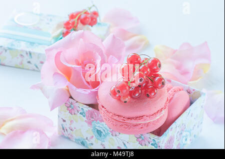 Makronen mit roten Johannisbeeren, Marshmallows auf dem Hintergrund der schönen Blumen Rosen in einer Geschenkbox. Nachtisch Nahaufnahme. Ein horizontaler Rahmen. Stockfoto