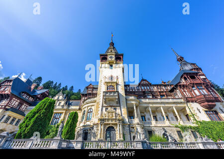 Tageslicht, Blick von unten nach verzierten Fassade von Schloss Peles mit Turm und der strahlend blaue Himmel mit Sonne Flare. Rumänische Könige Sommerresidenz in Carpa Stockfoto