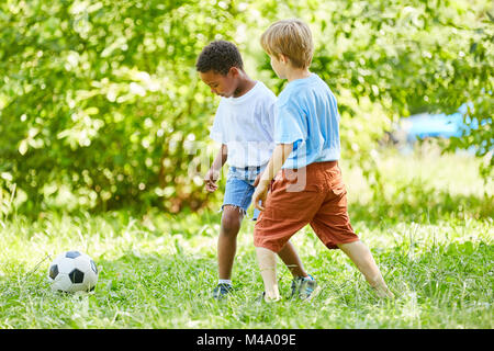 Zwei Jungen Fußball spielen im Sommer. Ferienhäuser im Park Stockfoto