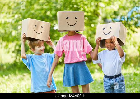 Drei Kinder spielen mit Fantasy mit lustigen bemalten Kartons im Garten Stockfoto