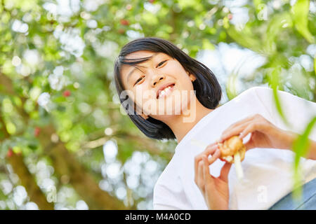 Asiatische Mädchen als Schülerin isst ein Baguette als Pause Brot Stockfoto