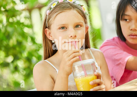 Mädchen Getränke frischer Orangensaft mit einem Strohhalm zum Frühstück Stockfoto