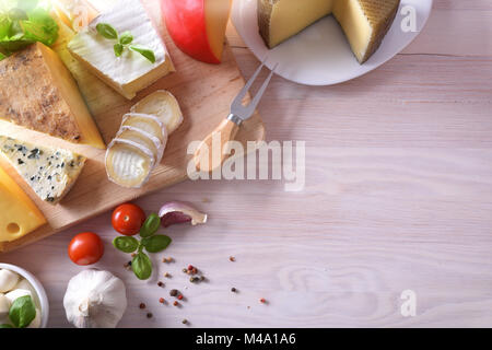 Verschiedene Arten von Käse, der auf einem weißen Holz- Tabelle dargestellt. Ansicht von oben. Horizontale Zusammensetzung Stockfoto