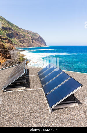 Reihen von Solarkollektoren auf dem Dach an Strand und Meer Stockfoto