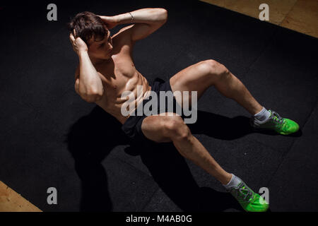 Muskulöser Mann Ausübung tun Übung sitzen. Athlet mit six-Pack, weißer Mann, kein Hemd Stockfoto