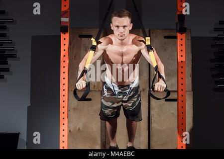 TRX Training. Crossfit Ausbilder an der Turnhalle tun TRX mehrere Personen nebeneinander trainieren. Stockfoto