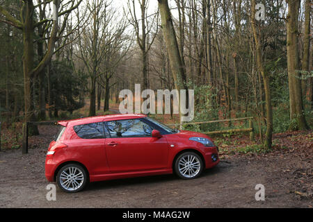 Rotes Auto in einem Wald Parkplatz in Worcestershire, Großbritannien geparkt. Stockfoto