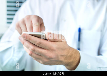 Arzt mit Handy. Person im weißen Mantel Eingabe smartphone. Stockfoto