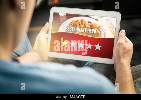 Schlechtes Restaurant überprüfen. Enttäuscht und unzufrieden Kunden schreckliche Bewertung mit Tablet-PC auf einer imaginären Kritik Website, Anwendung, Website. Stockfoto