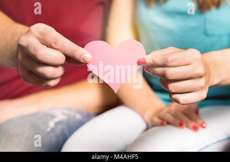 Glückliches Paar gleichen Herz aus Papier zusammenhalten. Der Mann und die Frau mit Pappe Liebe Symbol in der Hand. Valentinstag oder Geburtstag. Stockfoto