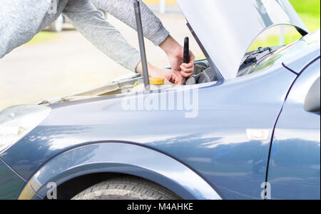 Mann zur Befestigung des Motors unter der Haube mit einer Monkey Wrench. Auto Reparatur, Wartung und Inspektion Konzept. Stockfoto