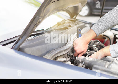 Mann zur Befestigung des Motors unter der Haube. Auto Reparatur, Wartung und Inspektion Konzept. Stockfoto