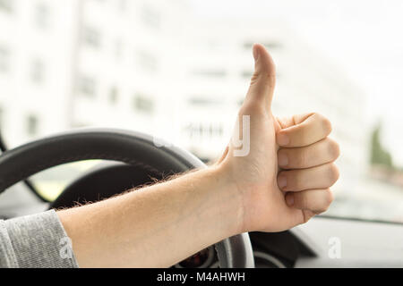 Gerne Fahrer mit Daumen nach oben im Auto. Mit neuen Auto oder kein Verkehr zufrieden. Fahrschule bestanden Prüfung oder Inspektion. Fahrzeug fixiert. Stockfoto