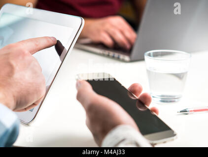 Casual business Leute treffen. Drei Freunde, die zusammen Arbeit im Büro mit modernen, mobilen und intelligenten Geräten. Austausch von Ideen, Teamarbeit. Stockfoto