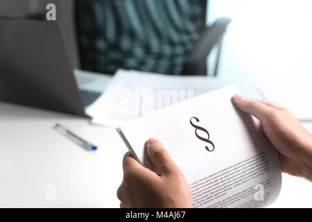 Mann hält ein juristisches Dokument in der Hand mit einem Abschnitt Home. Rechtsanwalt holding Gesetz Papier im Büro. Stockfoto