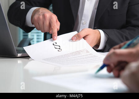 Rechtsanwalt, Rechtsberatung zu einem Client im Amt. Menschen in Anwaltskanzlei in treffen. Rechtsanwalt zeigt einen Abschnitt Zeichen auf Papier. Stockfoto