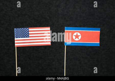 Die Flagge der Vereinigten Staaten von Amerika (USA) und Nordkorea aus Papier auf Holz stick gegen den dunklen Hintergrund. Stockfoto