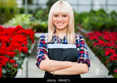 Junge lächelnde Frau florist stehend in einem Gewächshaus Stockfoto