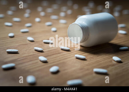 Drogensucht, medizinische Missbrauch und Drogen Haken und Abhängigkeit Konzept. Leere tablet Flasche durch viele Pillen auf dem Boden umgeben. Überdosierung Stockfoto