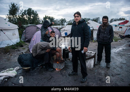 Eine Gruppe von afgan Menschen rund um das Feuer nach einigen Stunden intensiver Regen in die Dschungel von Calais. Stockfoto