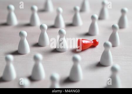 Rassismus, Mobbing, soziale Ausgrenzung, Depression und Einsamkeit Konzept. Eine Menge weißer Brettspiel Bauern, eine rote auf die Seite gefallen. Stockfoto