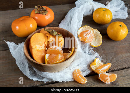 Frische Persimonen und Mandarinen Obst in der Schüssel Stockfoto