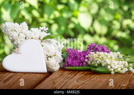 Herzen vor Maiglöckchen und Flieder Stockfoto