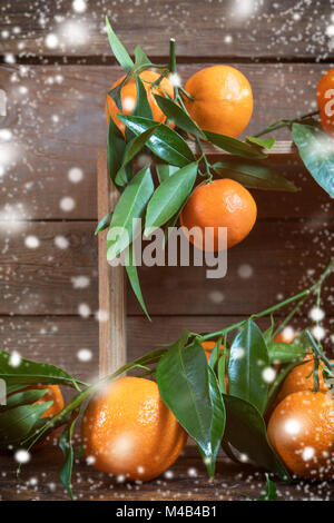 Mandarinen mit Blättern auf hölzernen Kasten Stockfoto