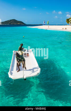 Kleines Boot in das türkisfarbene Wasser vor einem Sandstrand auf Palm Island, Grenadinen Inseln, St. Vincent und die Grenadinen, Karibik Stockfoto