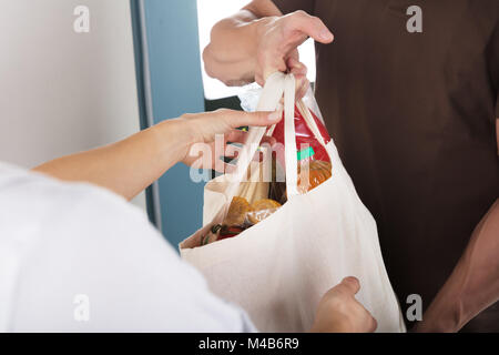 Nahaufnahme der Mann, der Beutel mit Lebensmittelgeschäft zu Frau zu Hause Stockfoto