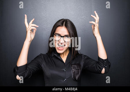 Wütend agressive Frau in Gläser zu schreien und halten sich an den Händen in der Nähe von Kopf isoliert auf Schwarz Stockfoto