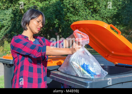 Niederländische Frau werfen plastik Müll im Thrash bin Stockfoto