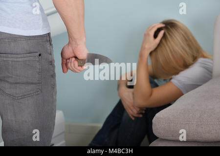 Nahaufnahme von einem Mann bedroht die Frau, die durch die scharfen Messer in seiner Hand. Stockfoto