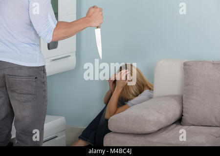 Nahaufnahme von einem Mann bedroht die Frau, die durch die scharfen Messer in seiner Hand. Stockfoto