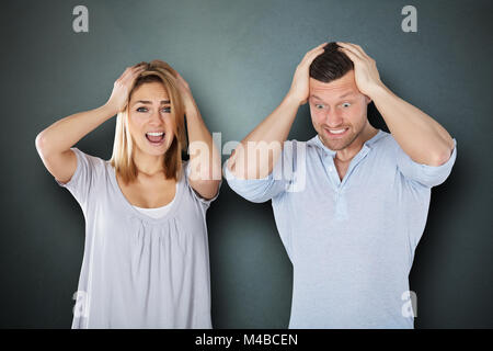 Portrait einer jungen frustriert Paar gegen grauer Hintergrund Stockfoto