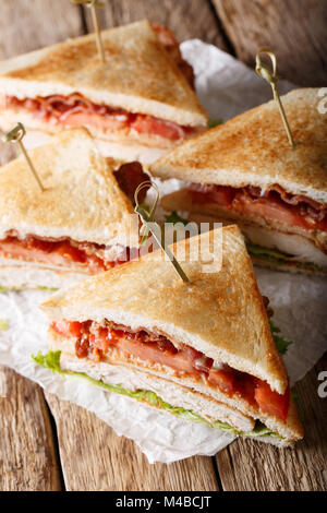 Club Sandwich mit der Türkei, Speck, Käse und Gemüse close-up auf dem Tisch. Vertikale Stockfoto