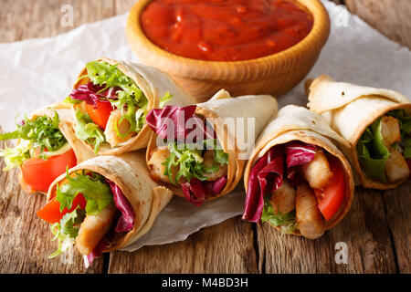 Frisch zubereitete Burritos mit der Türkei, Salat und Gemüse schließen bis auf ein Papier auf den Tisch. Horizontale Stockfoto