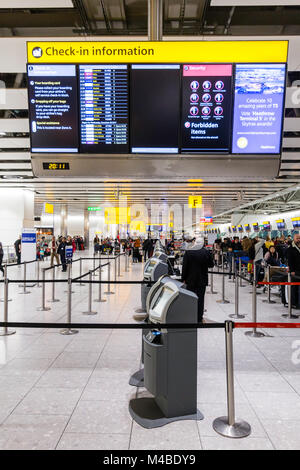 England, Heathrow Terminal 4. Leute anstellen an der Internationale Abflüge Schreibtische in der Kontrolle der mit Gepäck. Interieur. Nacht. Stockfoto