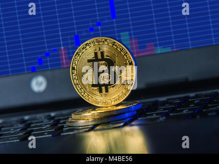 Golden bitcoin auf der Tastatur gegen Währung chart am PC-Bildschirm Stockfoto