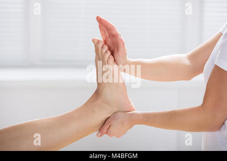 Nahaufnahme einer Physiotherapeutin, die Übung des Menschen Fuß Stockfoto