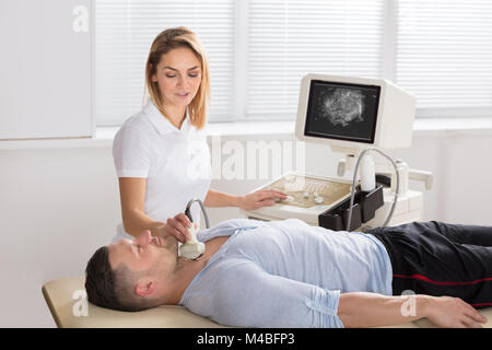 Junger Mann, Ultraschall am Hals durch weibliche Arzt in einer Klinik Stockfoto