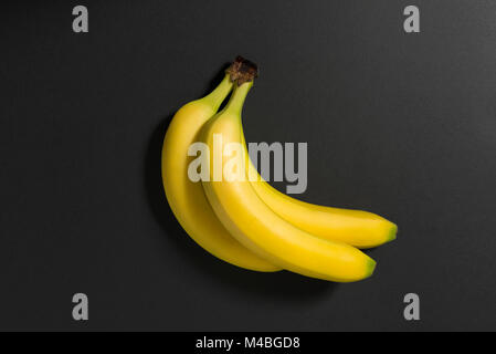 Drei Bananen auf schwarzem Hintergrund Stilleben Bild. Stockfoto